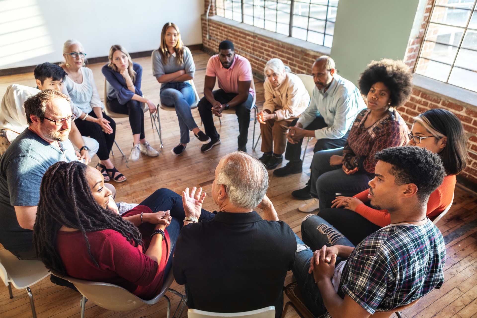 Diverse group in a circle, discussing in a bright room.